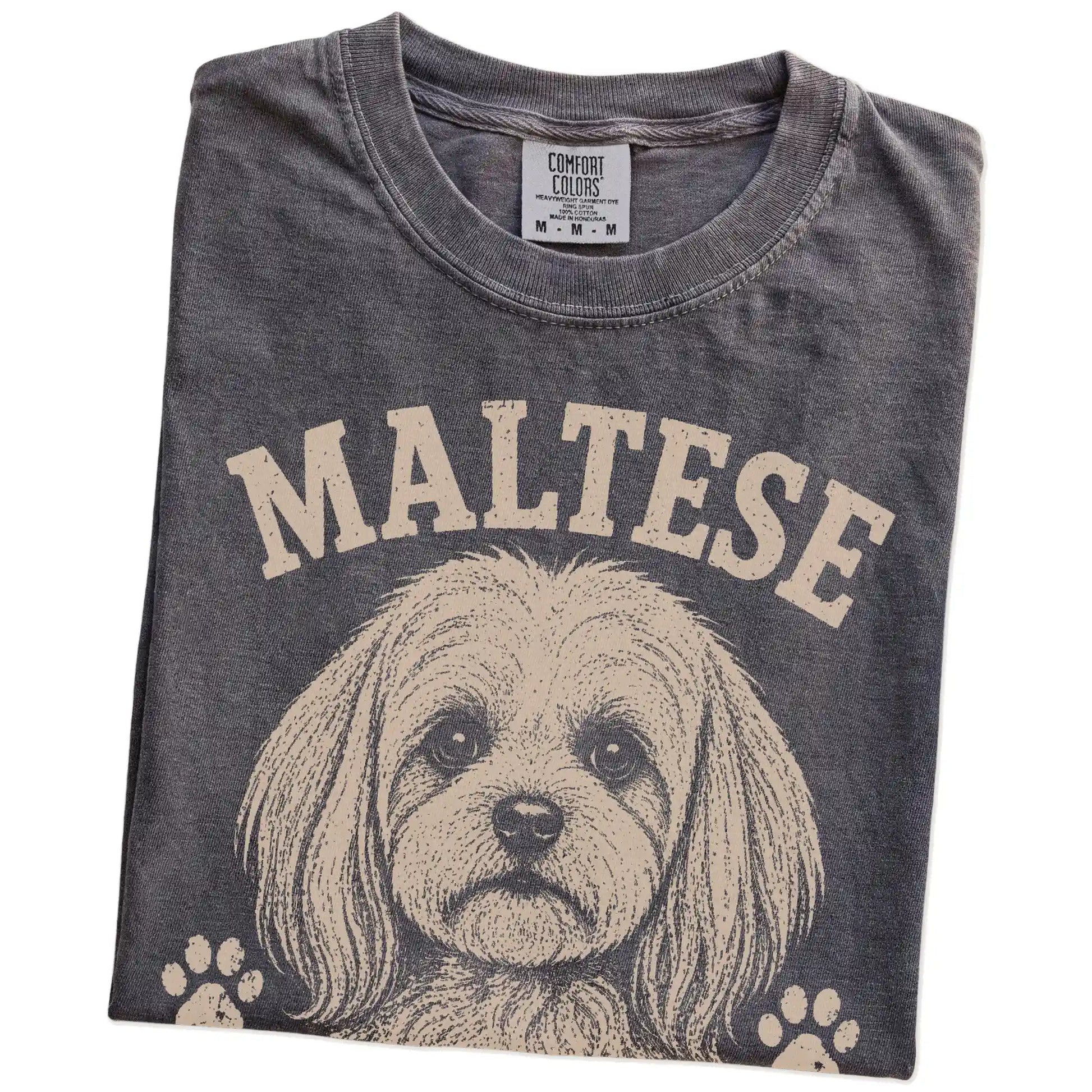 Folded Pepper Comfort Colors® T-shirt showing Maltese design with “Tiny, Polished & Totally In Charge” lettering