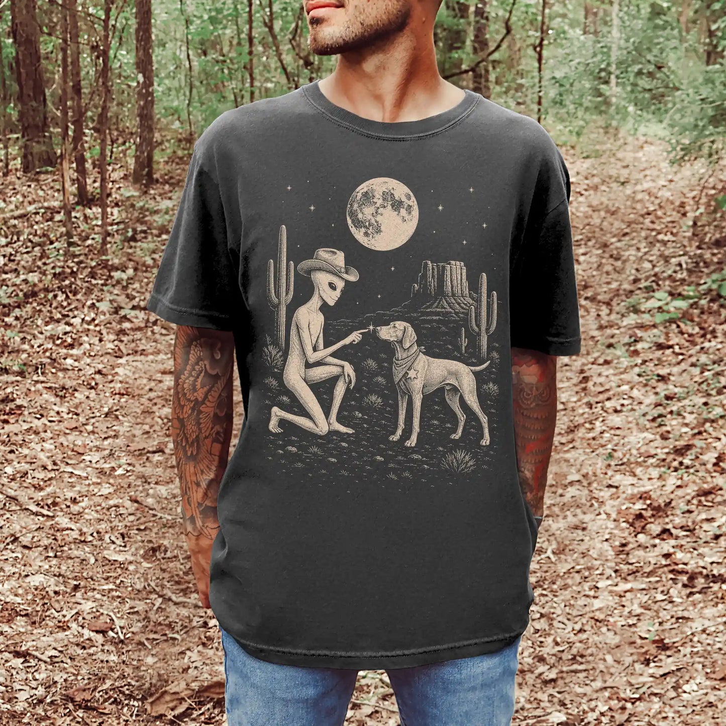 Model wearing a Pepper Comfort Colors® T-shirt with cowboy alien fist-bumping a vizsla beneath the moon