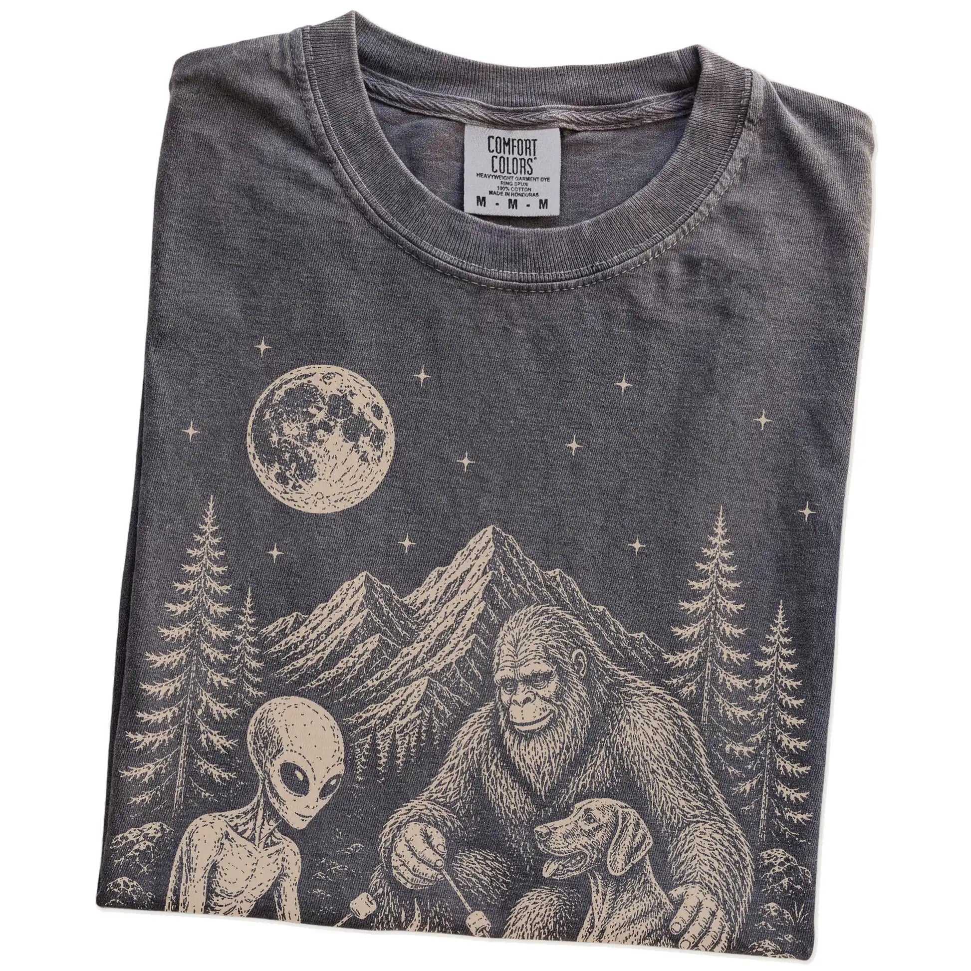 Folded Pepper Comfort Colors® T-shirt showing Weimaraner camping with Bigfoot and an alien