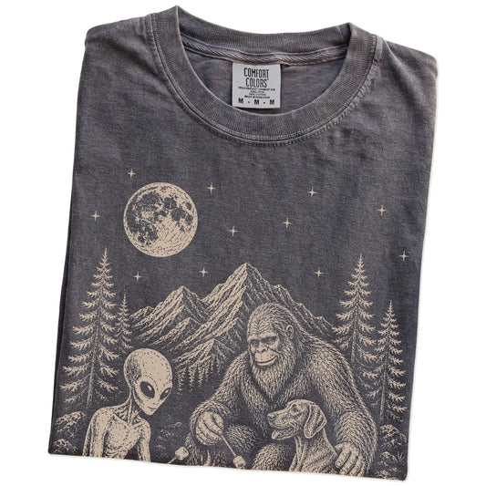 Folded Pepper Comfort Colors® T-shirt showing Weimaraner camping with Bigfoot and an alien