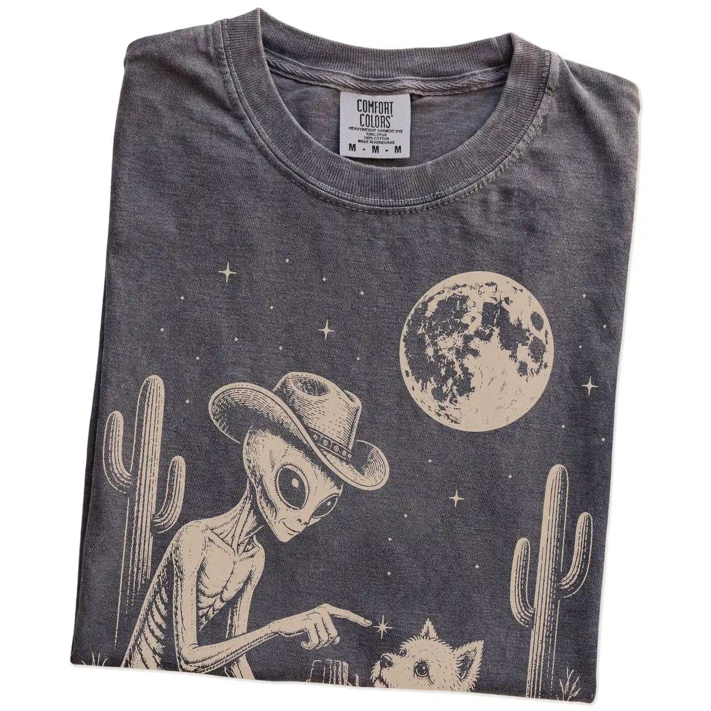 Folded Pepper Comfort Colors® T-shirt showing cowboy alien fist-bumping a westie beneath the moon