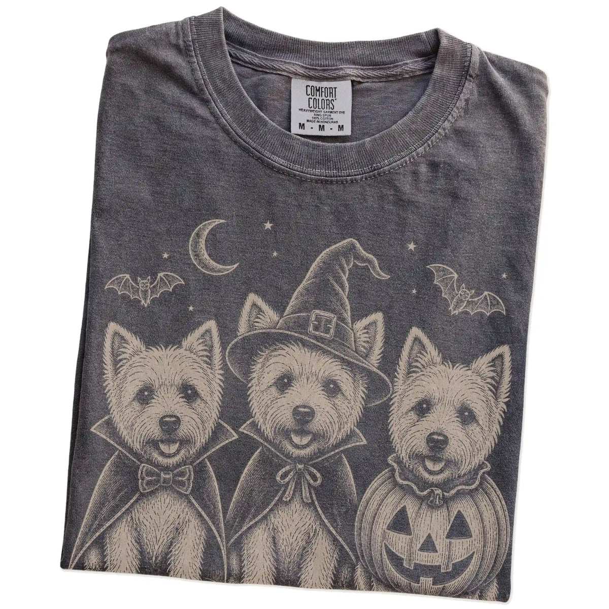 Folded Pepper Comfort Colors® T-shirt showing three Westie dogs dressed for Halloween beneath bats and a crescent moon