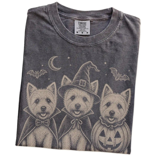 Folded Pepper Comfort Colors® T-shirt showing three Westie dogs dressed for Halloween beneath bats and a crescent moon