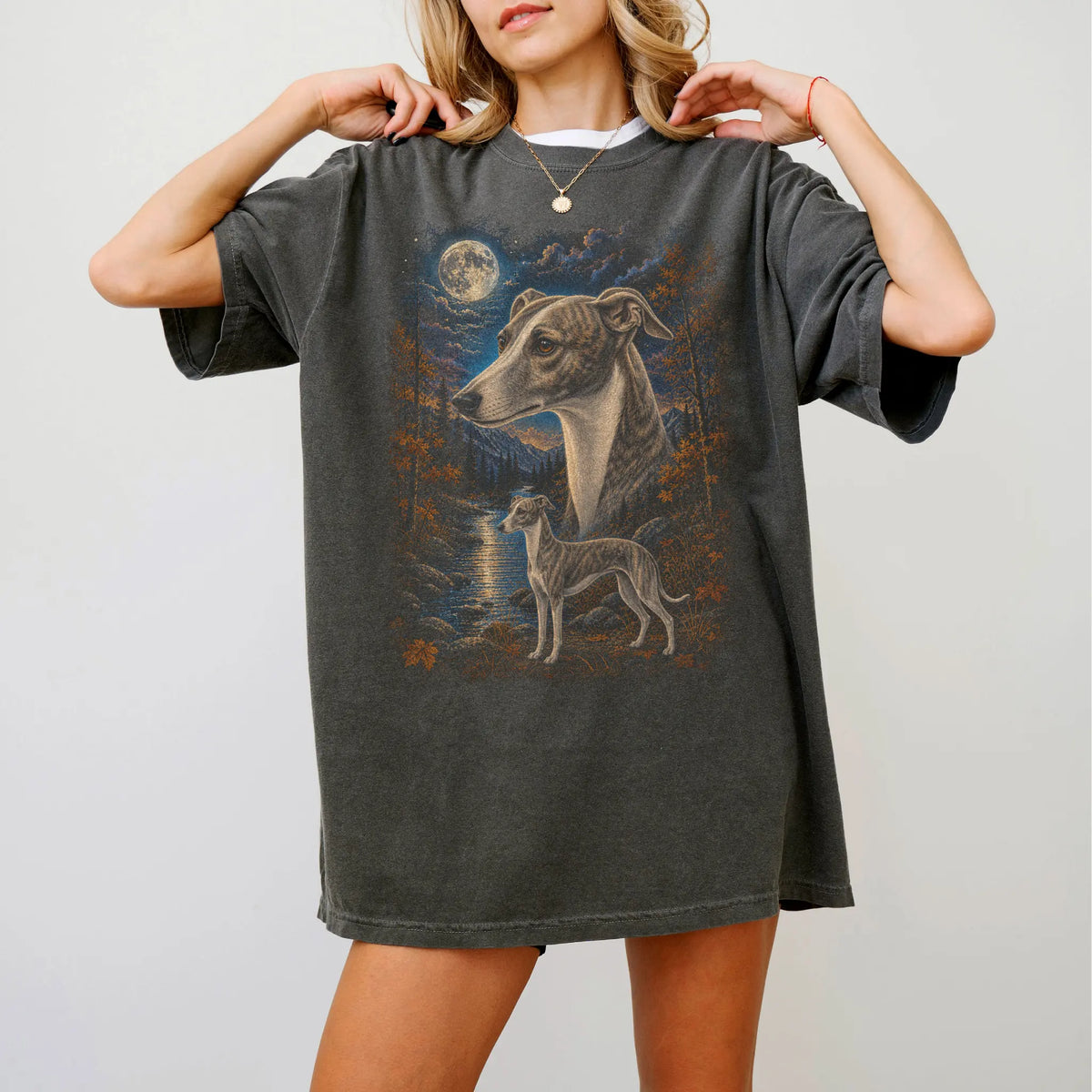 Model wearing a Pepper Comfort Colors® t-shirt featuring Whippet in a moonlit fall forest