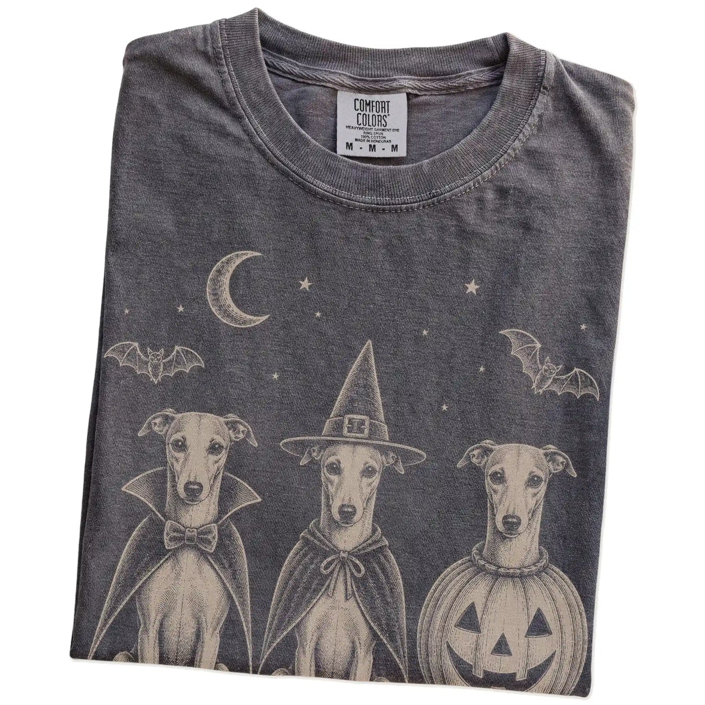 Folded Pepper Comfort Colors® T-shirt showing three Whippet dogs dressed for Halloween beneath bats and a crescent moon
