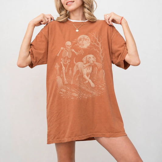 Model wearing a Yam Comfort Colors® T-shirt showing Vizsla running through a moonlit graveyard with a chasing skeleton