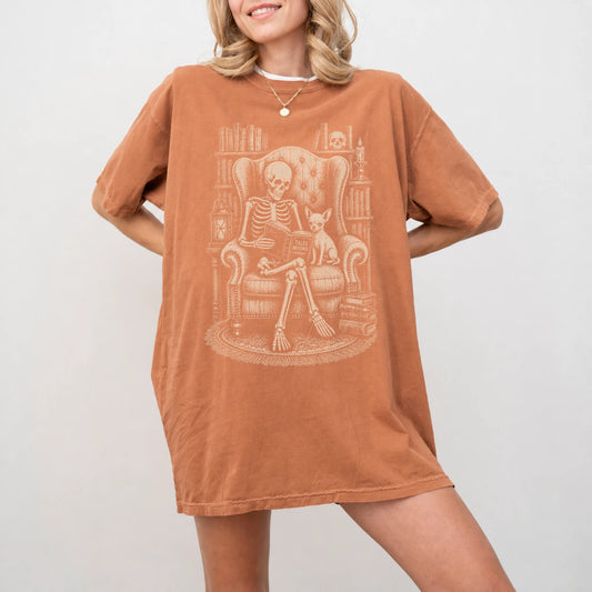 Model wearing a Yam Comfort Colors® T-shirt showing skeleton reading in a library beside a Chihuahua