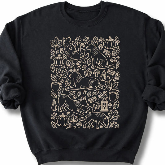 Blue Heeler among autumn leaves and seasonal icons on a black sweatshirt.