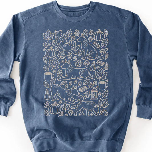 Blue Heeler among autumn leaves and seasonal icons on a denim sweatshirt.