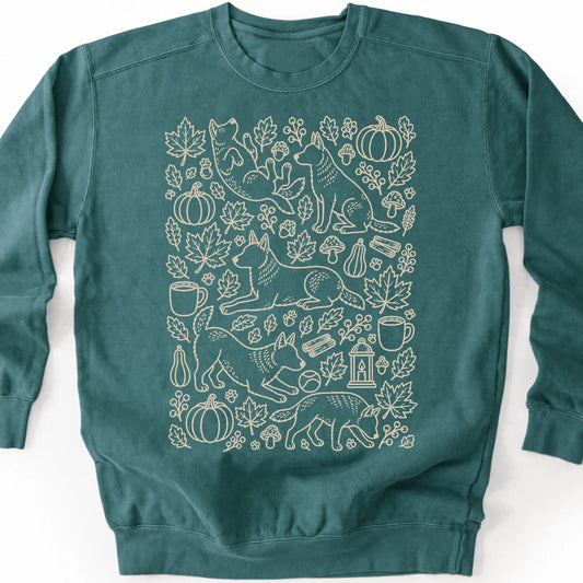 Blue Heeler among autumn leaves and seasonal icons on a blue spruce sweatshirt.