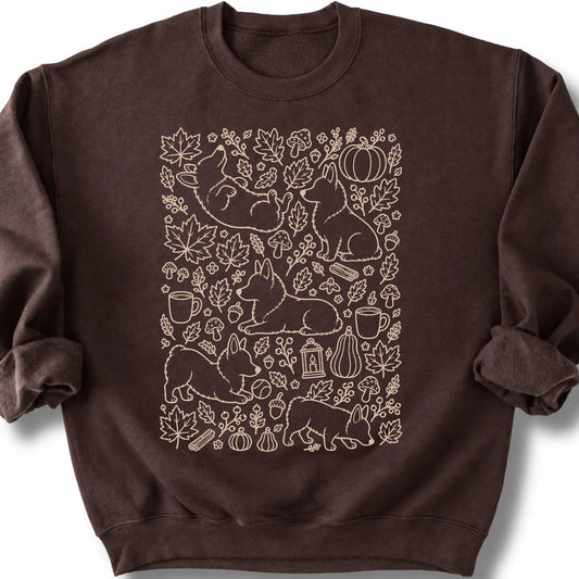 Corgi among autumn leaves and seasonal icons on a dark chocolate sweatshirt.