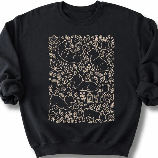 Corgi among autumn leaves and seasonal icons on a black sweatshirt.