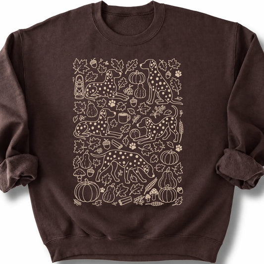 Dalmatian among autumn leaves and seasonal icons on a dark chocolate sweatshirt.