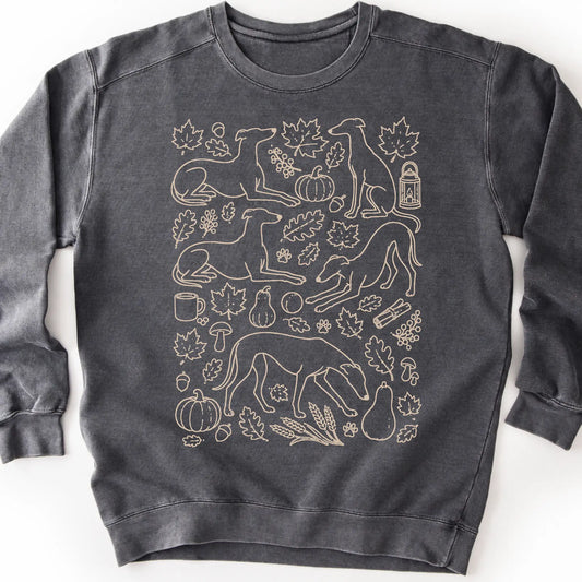 Greyhound among autumn leaves and seasonal icons on a pepper sweatshirt.