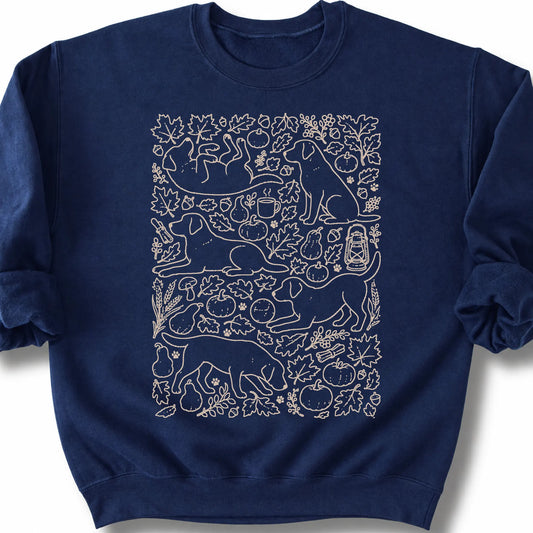 Labrador Retriever among autumn leaves and seasonal icons on a navy sweatshirt.