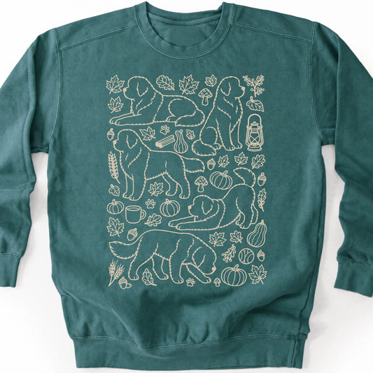 Newfie among autumn leaves and seasonal icons on a blue spruce sweatshirt.