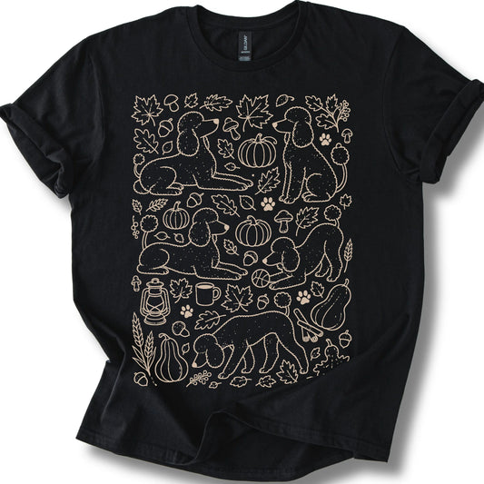 Poodle among autumn leaves and seasonal icons on a black T-shirt.