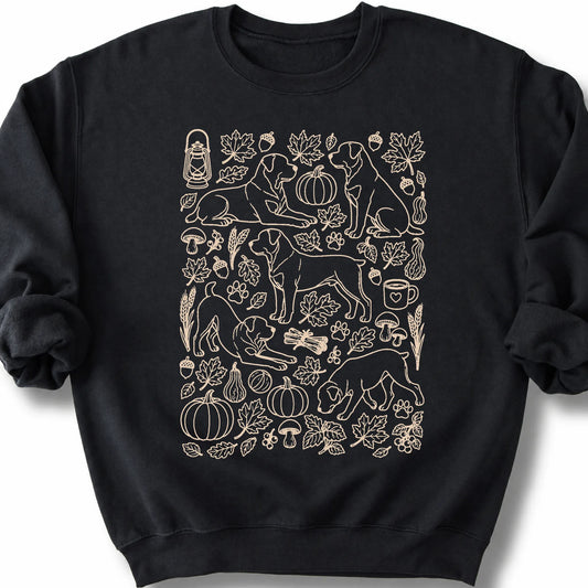 Rottweiler among autumn leaves and seasonal icons on a black sweatshirt.