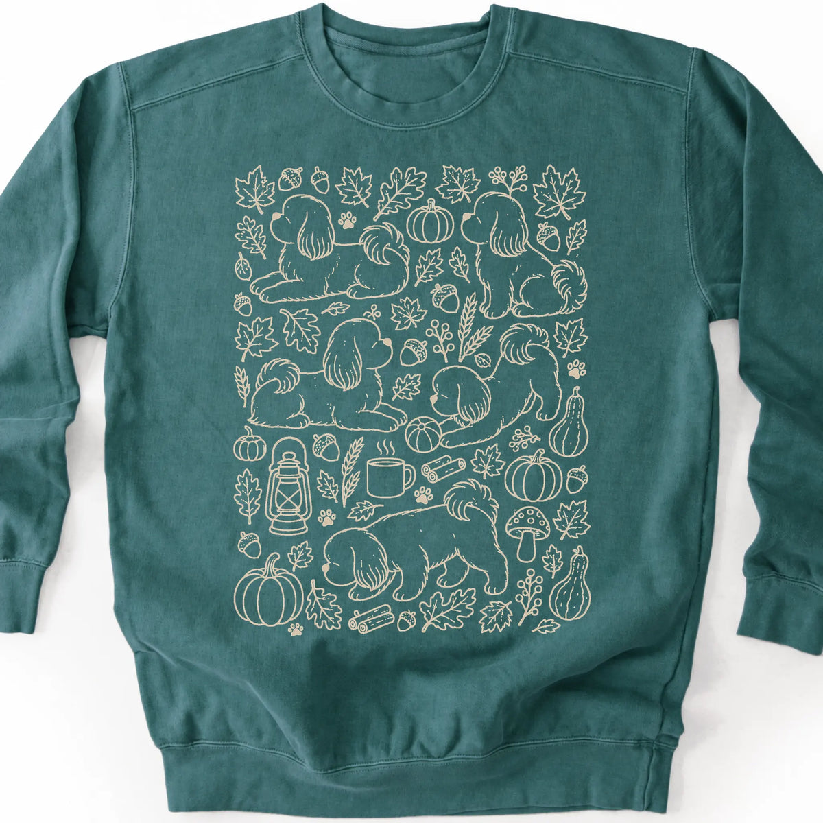 Shih Tzu among autumn leaves and seasonal icons on a blue spruce sweatshirt.