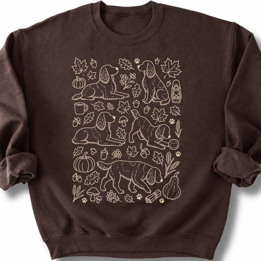 Springer Spaniel among autumn leaves and seasonal icons on a dark chocolate sweatshirt.