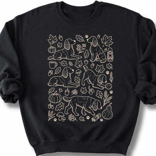 Springer Spaniel among autumn leaves and seasonal icons on a black sweatshirt.