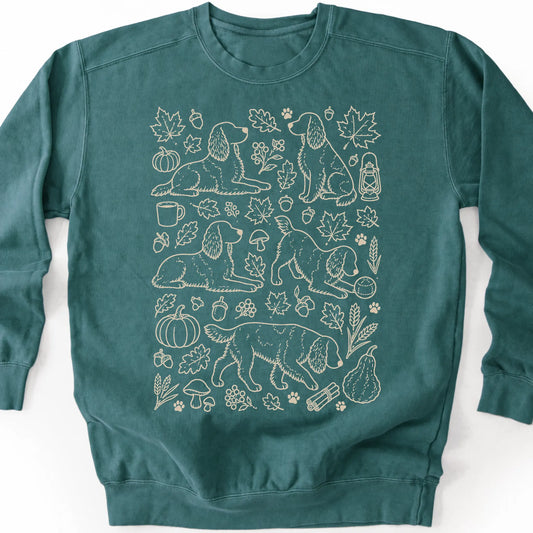Springer Spaniel among autumn leaves and seasonal icons on a blue spruce sweatshirt.