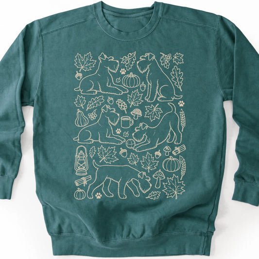Standard Schnauzer among autumn leaves and seasonal icons on a blue spruce sweatshirt.
