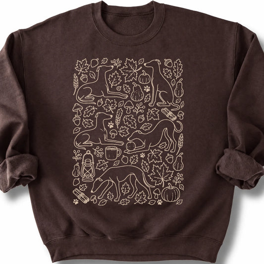 Whippet among autumn leaves and seasonal icons on a dark chocolate sweatshirt.