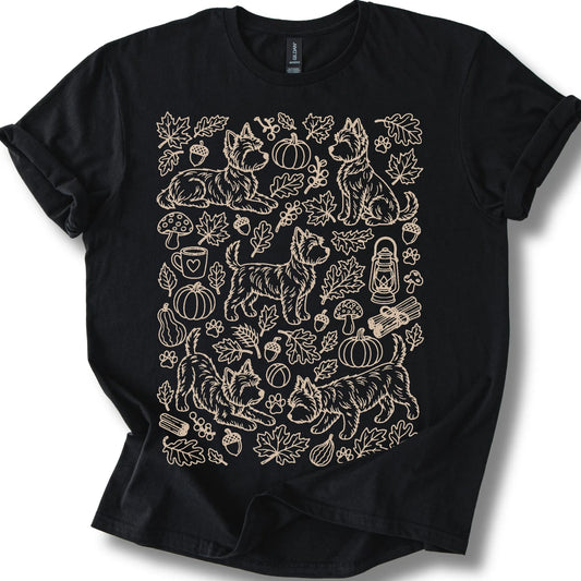 Yorkie among autumn leaves and seasonal icons on a black T-shirt.