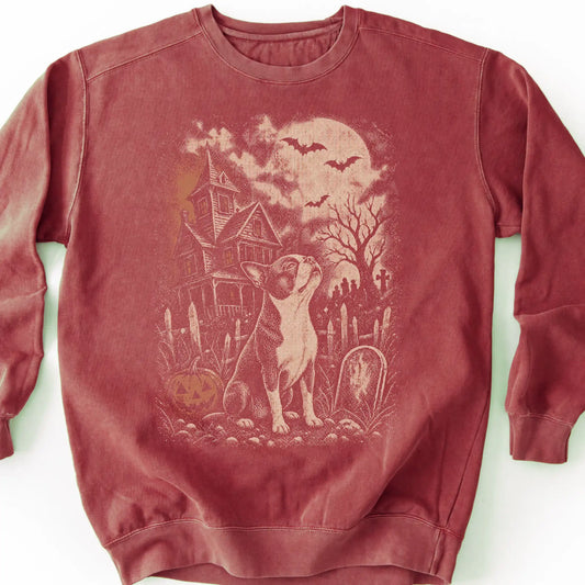 Boston Terrier beside a haunted house on a crimson sweatshirt.