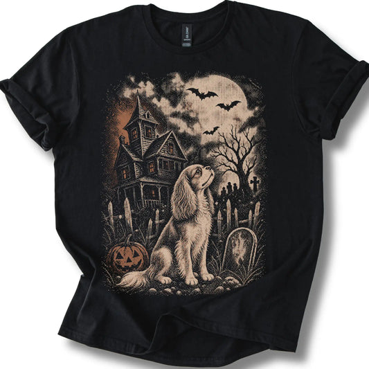 Cavalier King Charles Spaniel beside a haunted house on a black T-shirt.