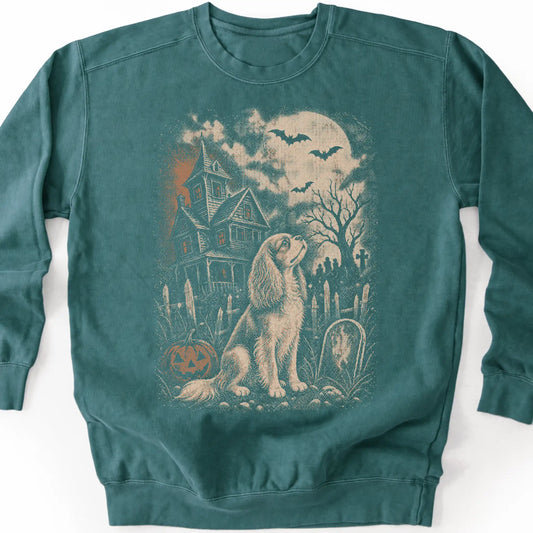 Cavalier King Charles Spaniel beside a haunted house on a blue spruce sweatshirt.