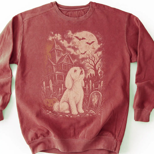 Maltese beside a haunted house on a crimson sweatshirt.